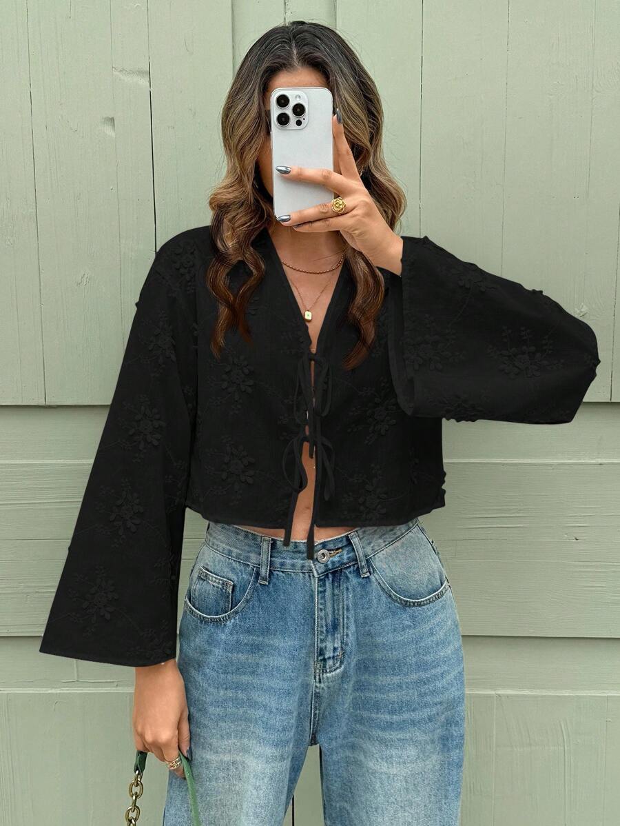 Person wearing a black cardigan and blue jeans taking a mirror selfie.