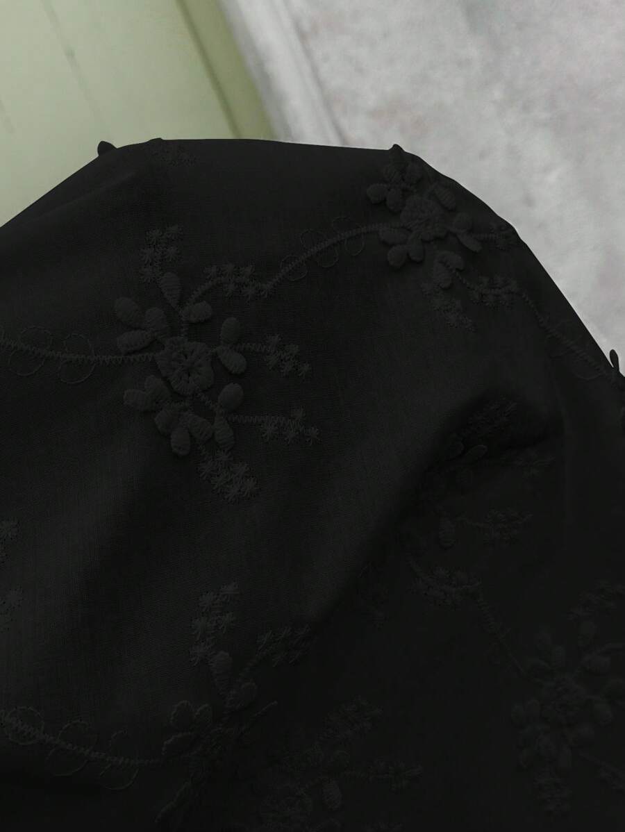 Black fabric with floral embroidery on a light background