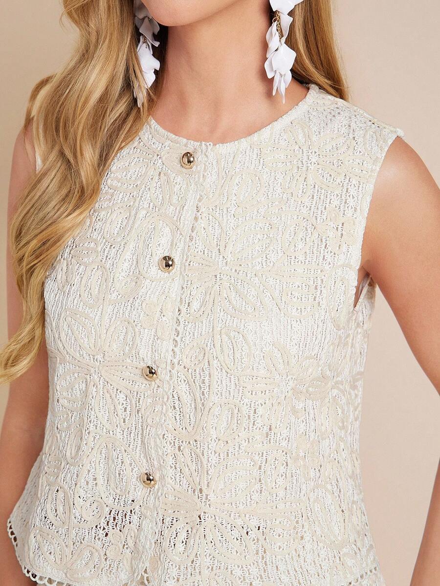 Close-up of a person wearing a white textured sleeveless top with gold buttons on a beige background.