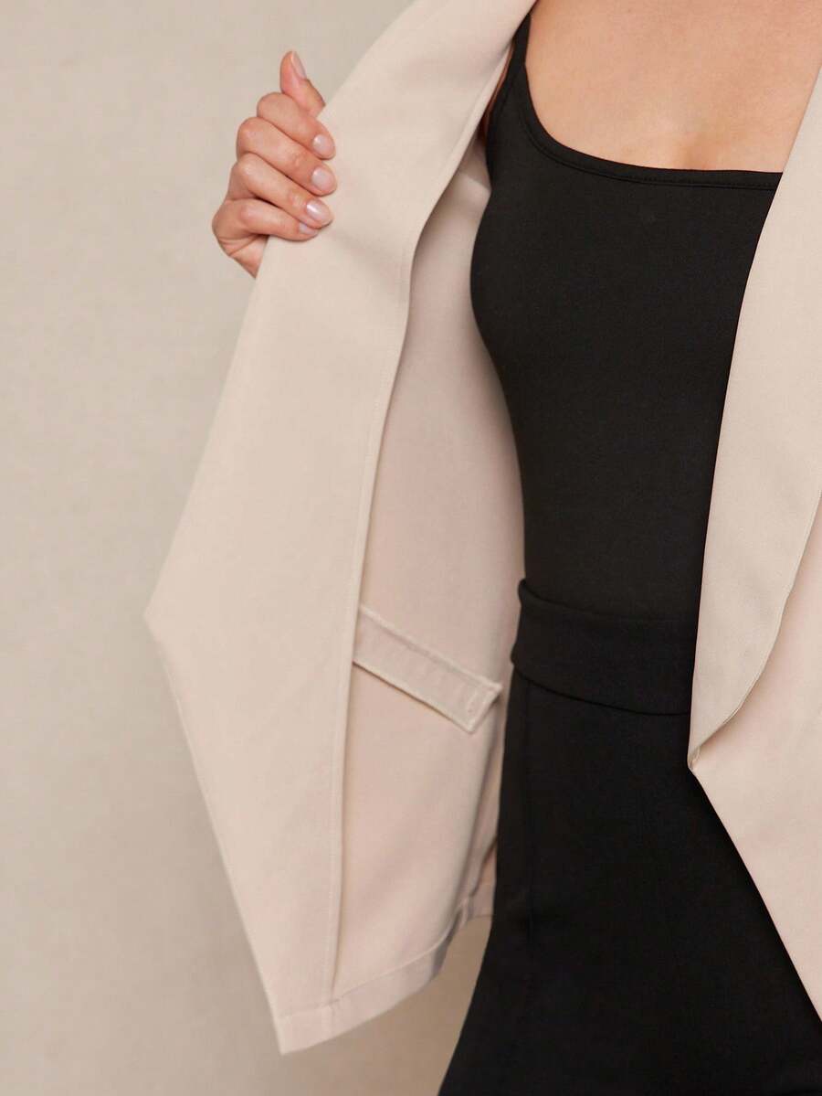 Person wearing a beige cardigan over a black top against a neutral background