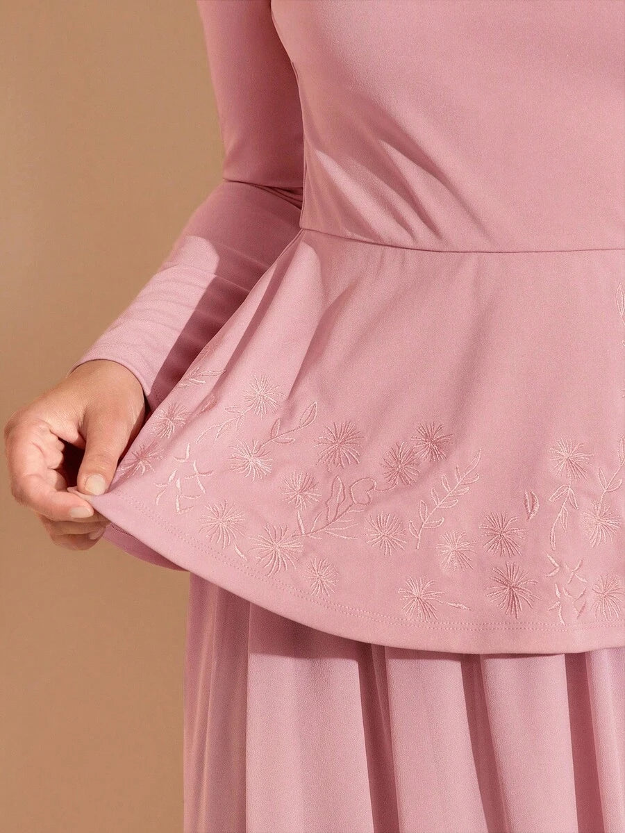 Close-up of a pink dress with floral embroidery on a beige background