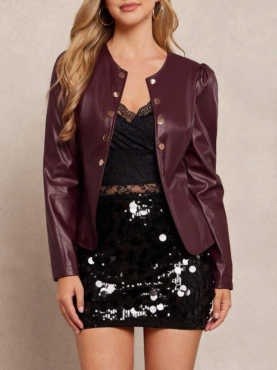 Woman wearing a burgundy leather jacket over a black dress with sequin details on a beige background