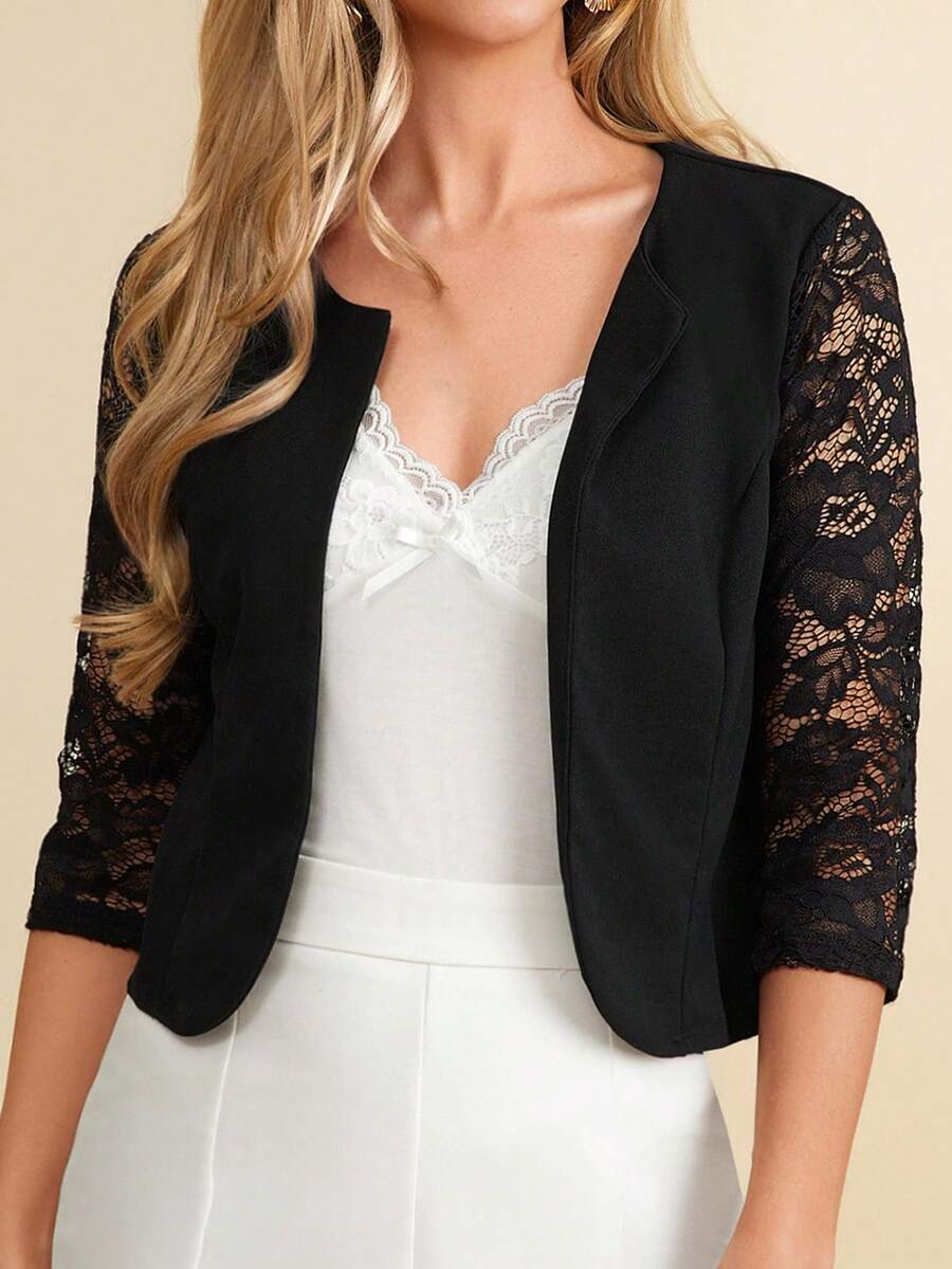 Black blazer with lace sleeves over a white dress on a beige background