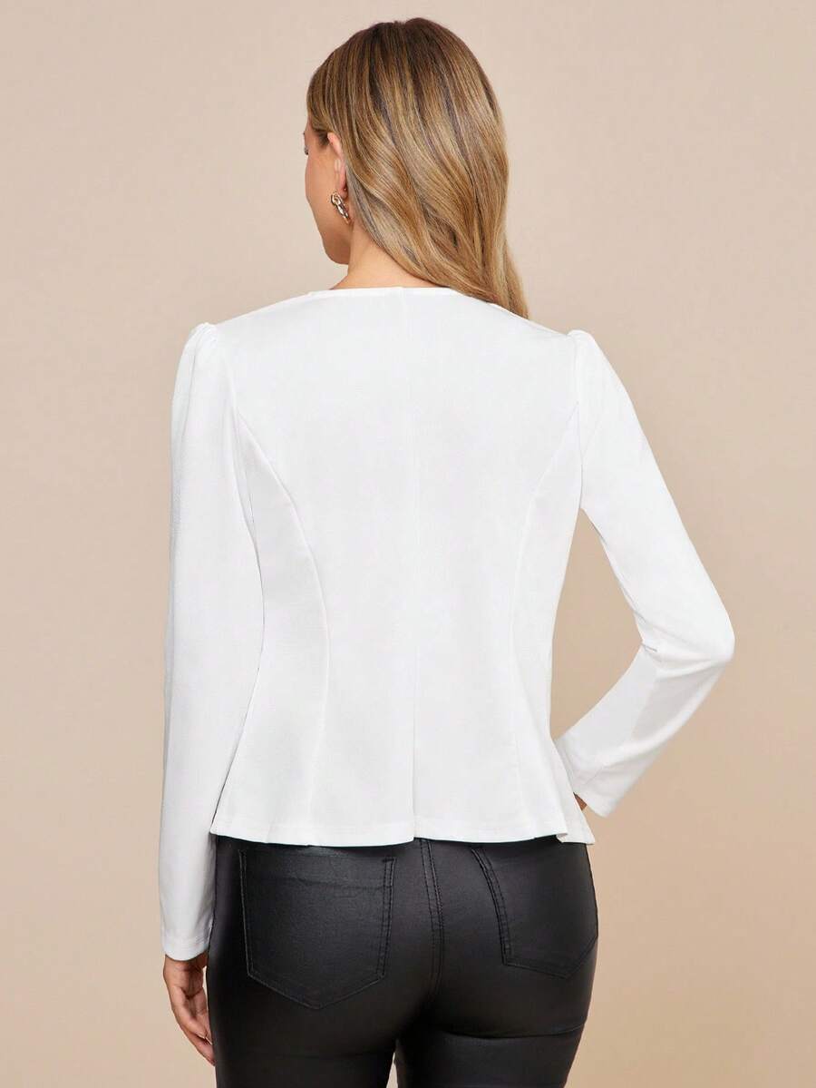 Woman wearing a white blazer and black pants on a beige background
