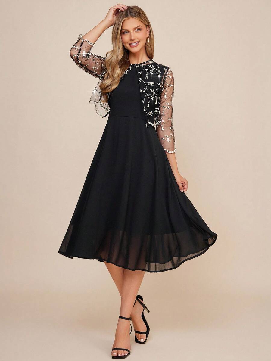 Woman wearing a black dress with sheer sleeves on a beige background