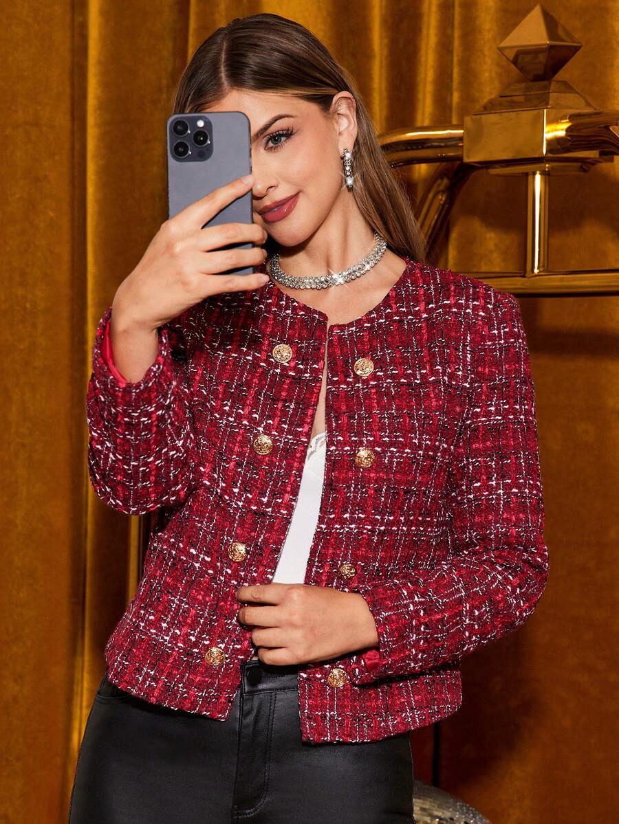 Woman taking a mirror selfie wearing a red tweed jacket indoors.