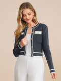 Woman wearing a navy blue cardigan with white trim on a beige background