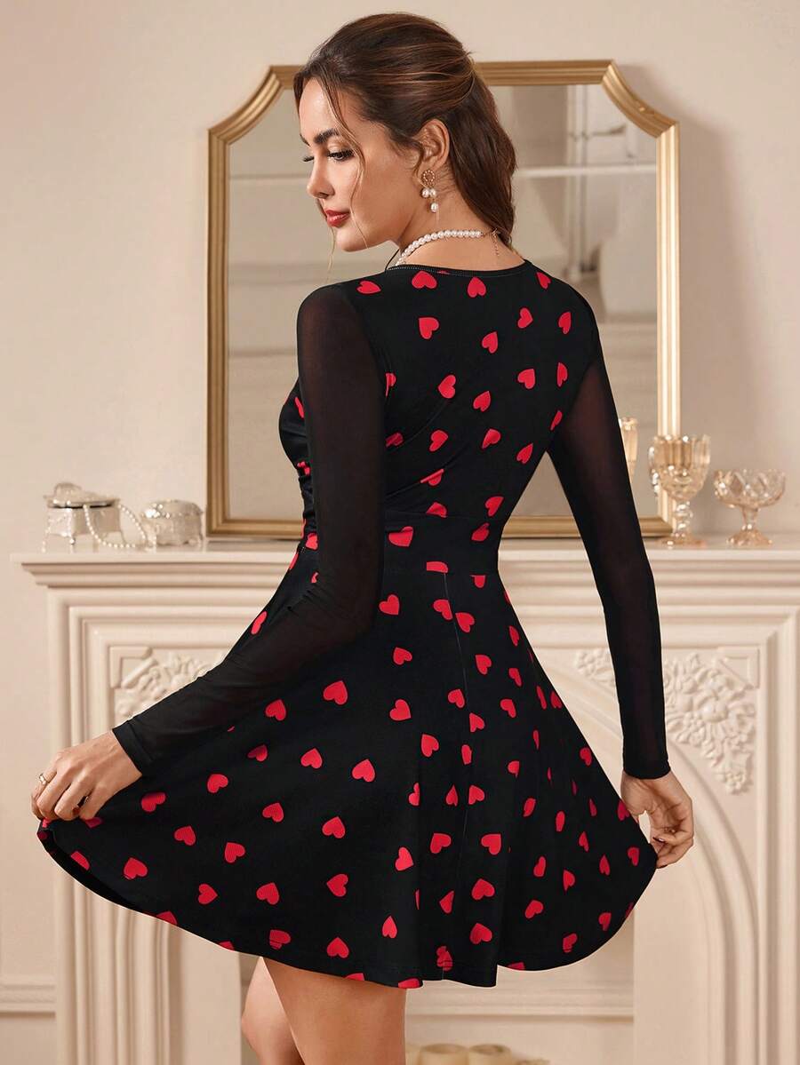 Woman wearing a black dress with red heart patterns in a room with decorative elements.