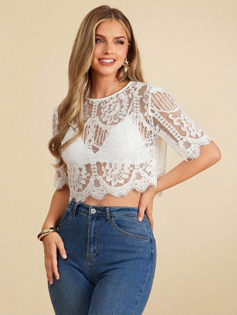 Woman wearing a white lace top and blue jeans on a beige background