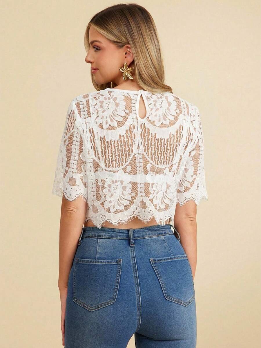 Woman wearing a white lace top and blue jeans on a beige background