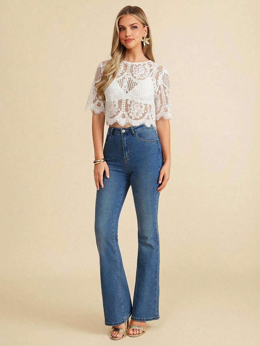 Woman wearing a white lace top and blue jeans on a beige background