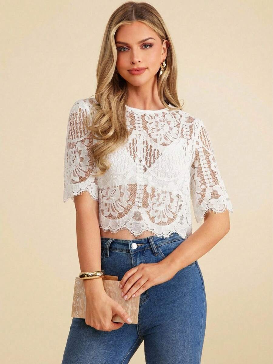 Woman wearing a white lace top and blue jeans on a beige background