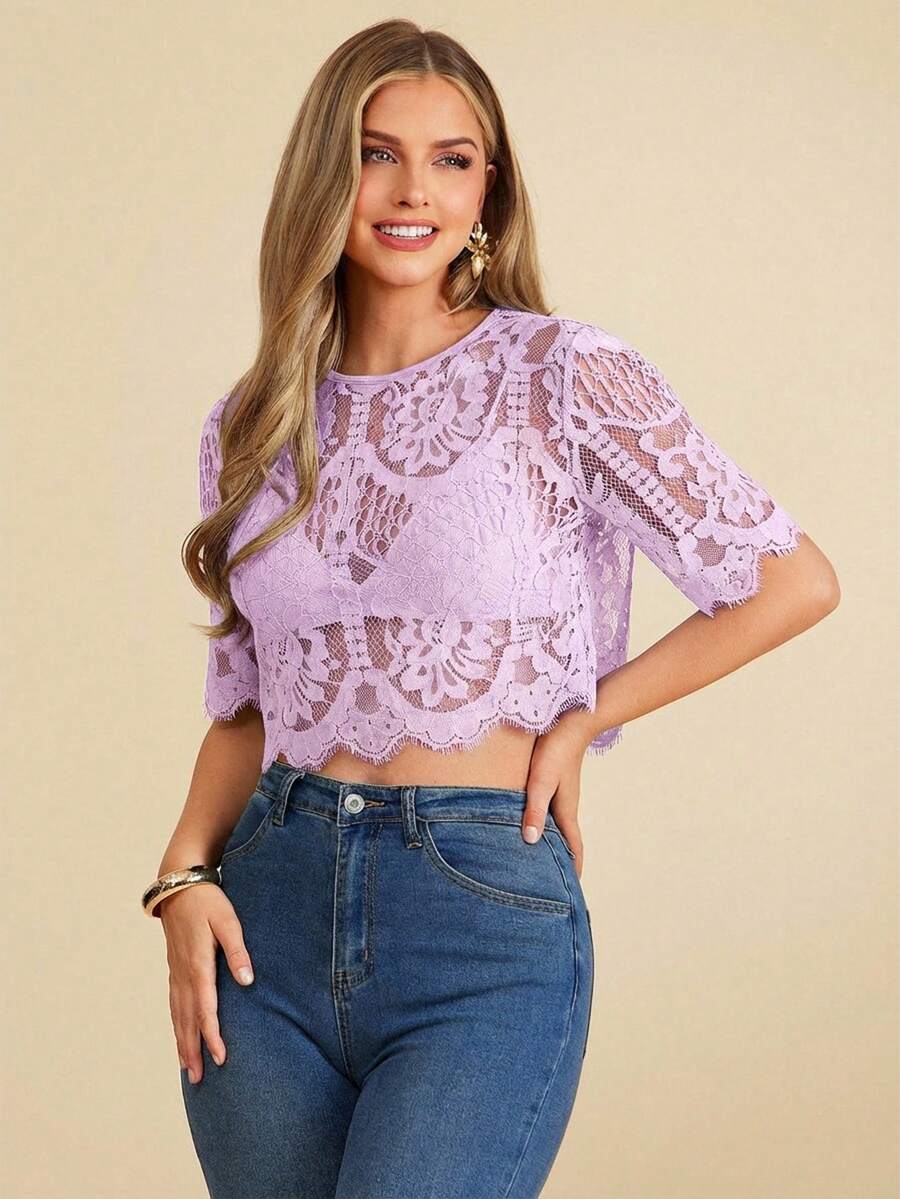 Woman wearing a purple lace top and blue jeans on a beige background