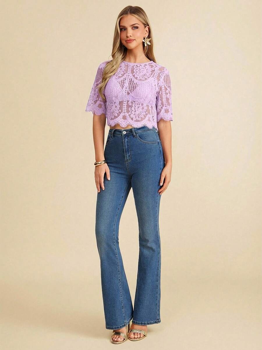 Woman wearing a purple lace top and blue jeans on a beige background