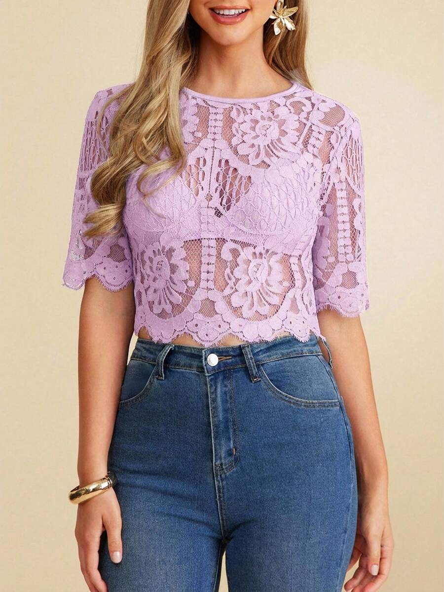 Woman wearing a purple lace top and blue jeans on a beige background