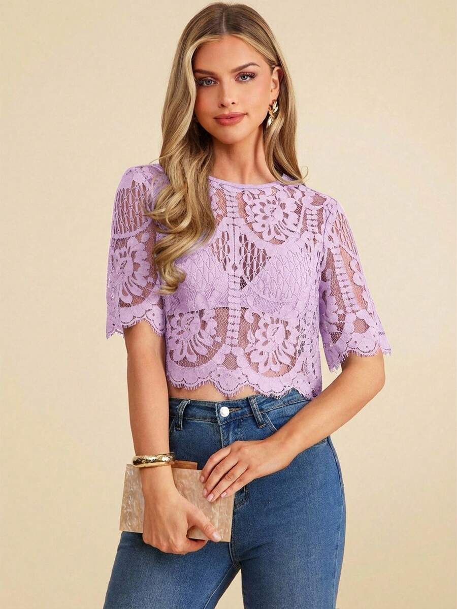 Woman wearing a purple lace top and blue jeans on a beige background