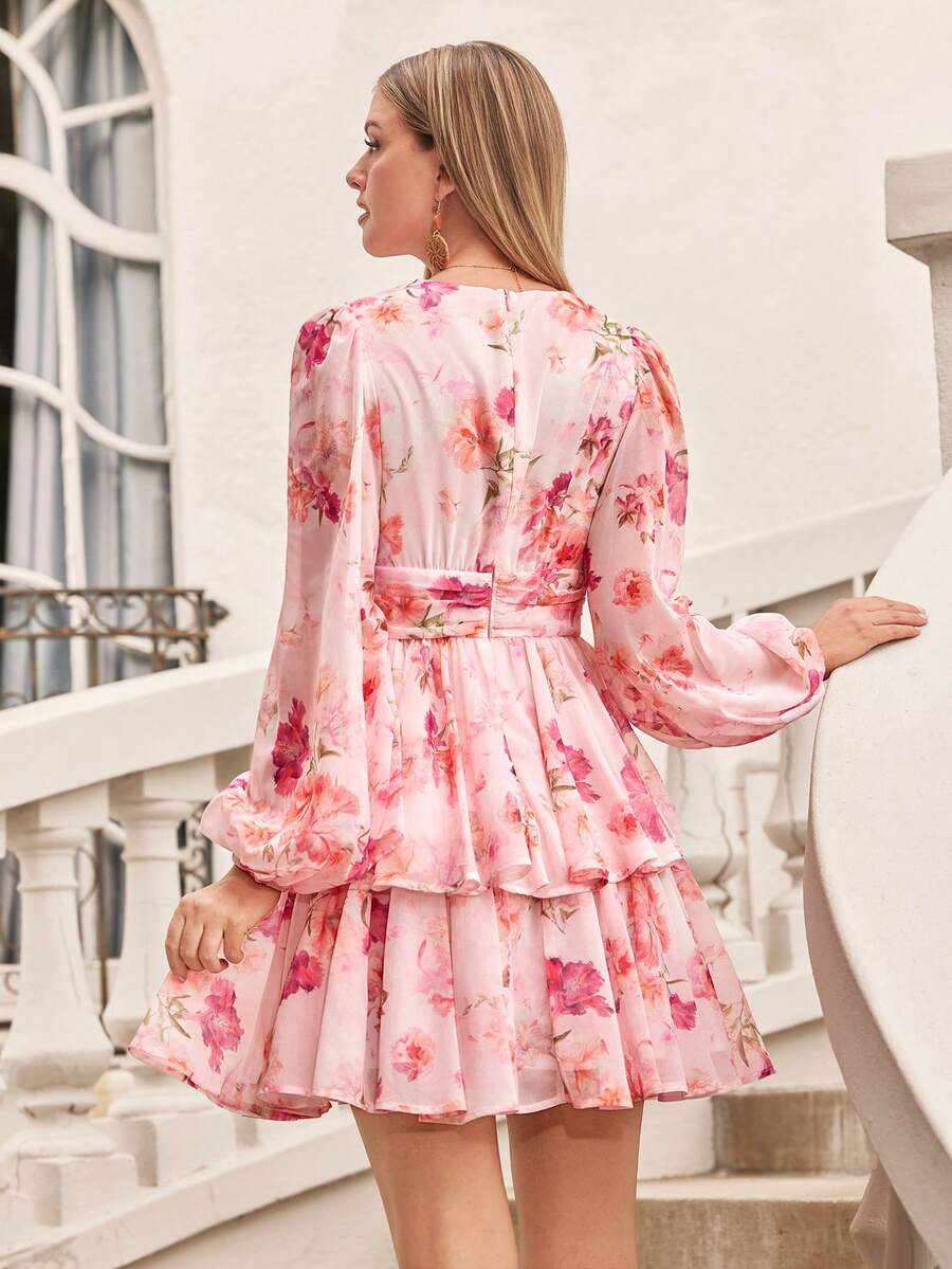 Woman wearing a pink floral dress standing on a balcony.