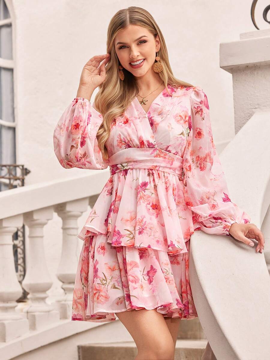 Woman wearing a pink floral dress standing on a staircase.