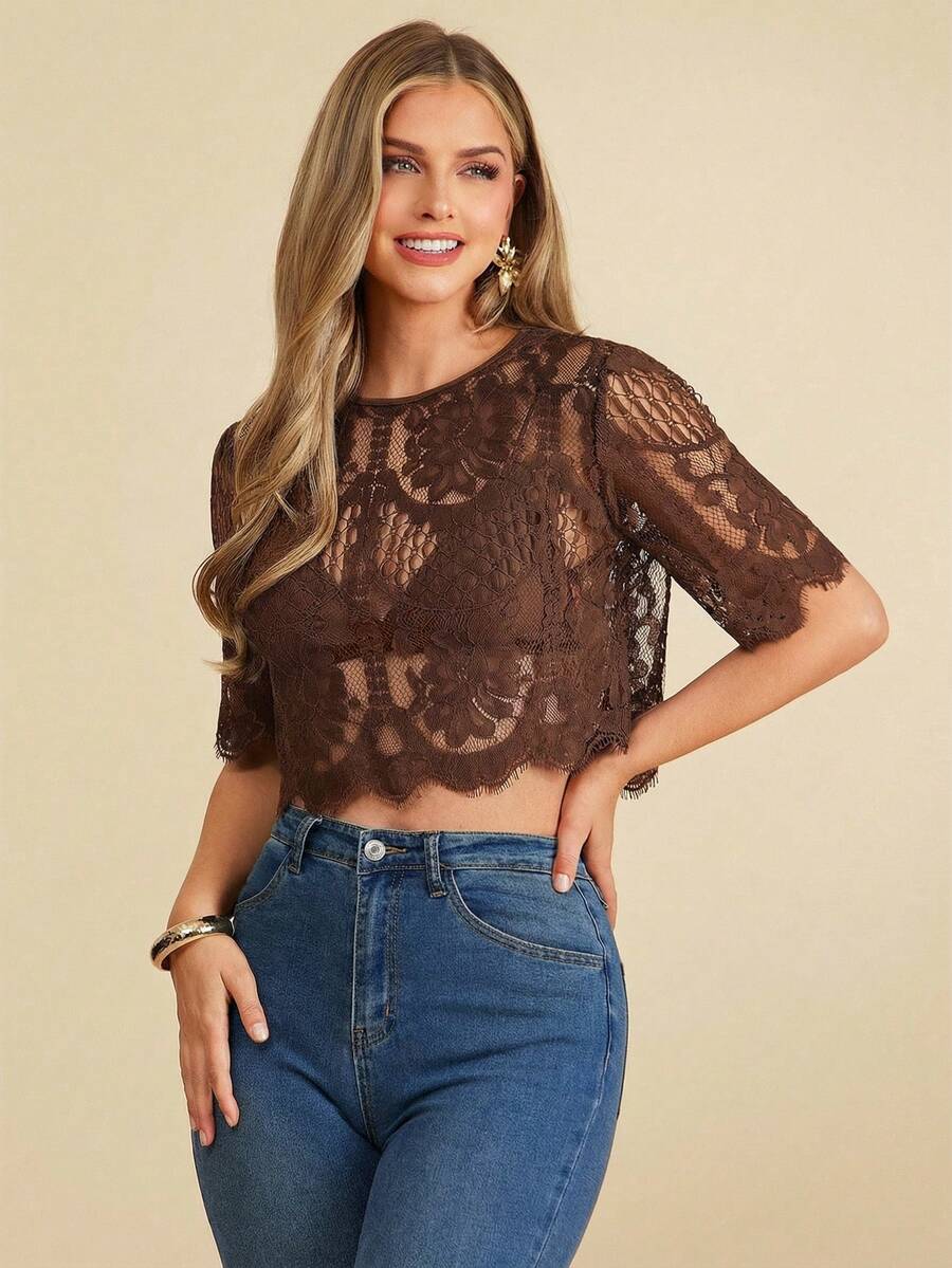 Woman wearing a brown lace top and blue jeans on a beige background