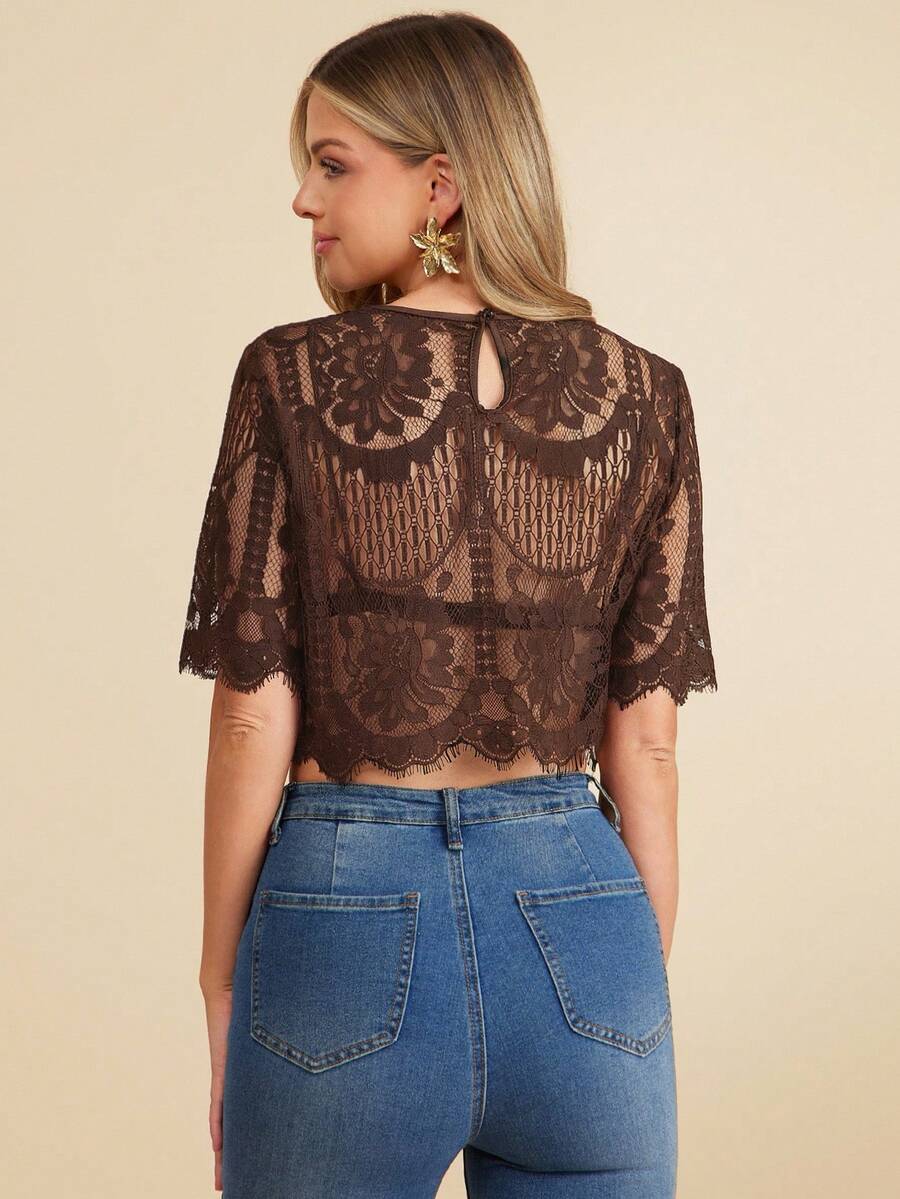 Woman wearing a brown lace top and blue jeans on a beige background