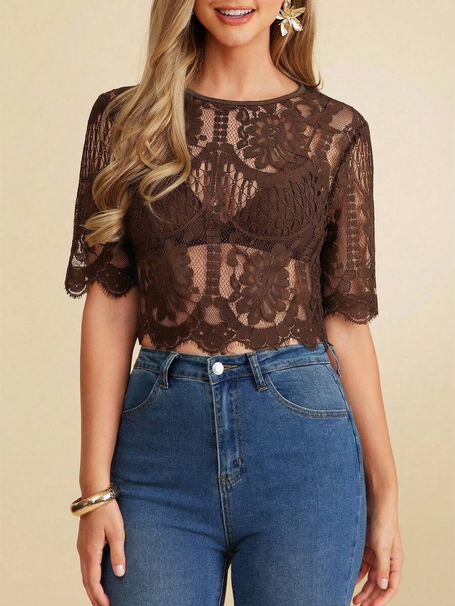 Woman wearing a brown lace top and blue jeans on a beige background