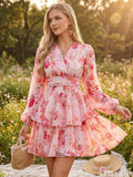 Woman in a floral dress standing in a field with a straw bag and hat.