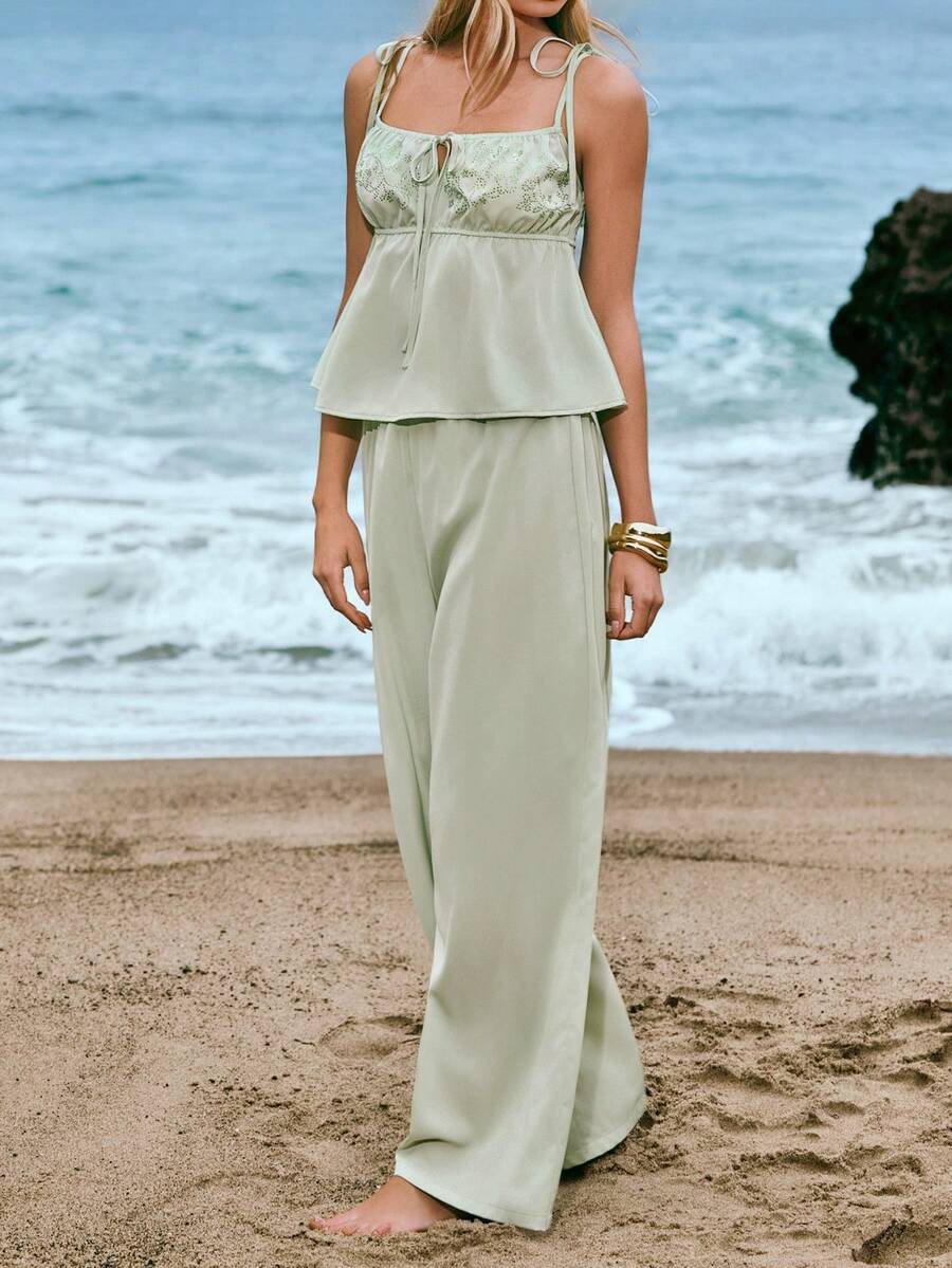 Woman wearing a light green top and pants with a beige background
