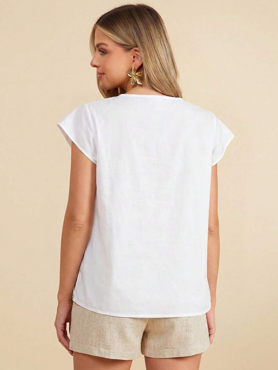 Woman wearing a white top and beige shorts against a beige background