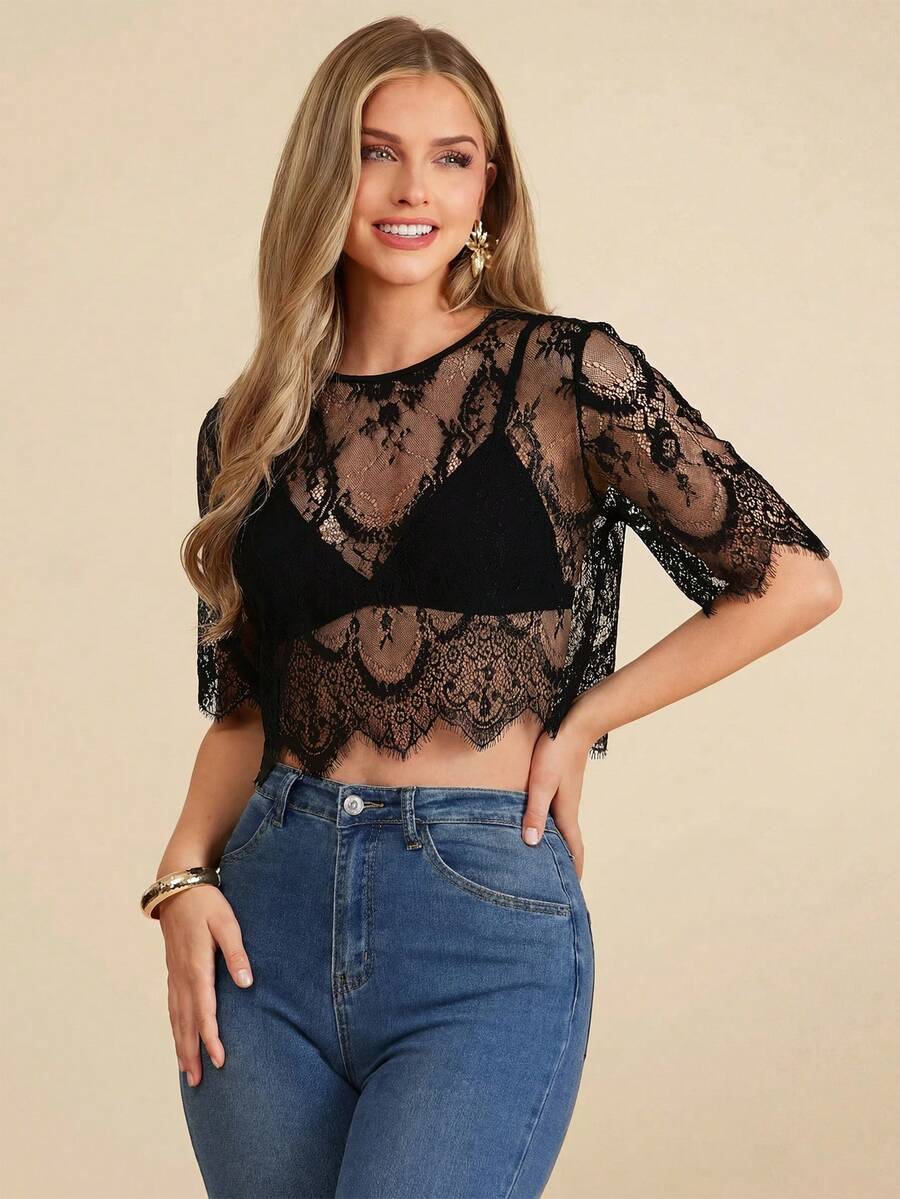 Woman wearing a black lace top and blue jeans on a beige background