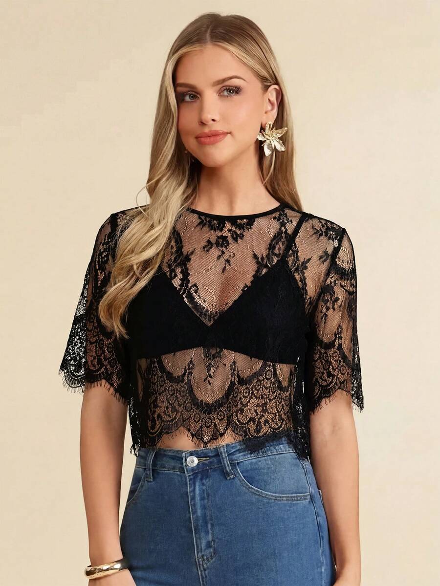 Woman wearing a black lace top and blue jeans on a beige background